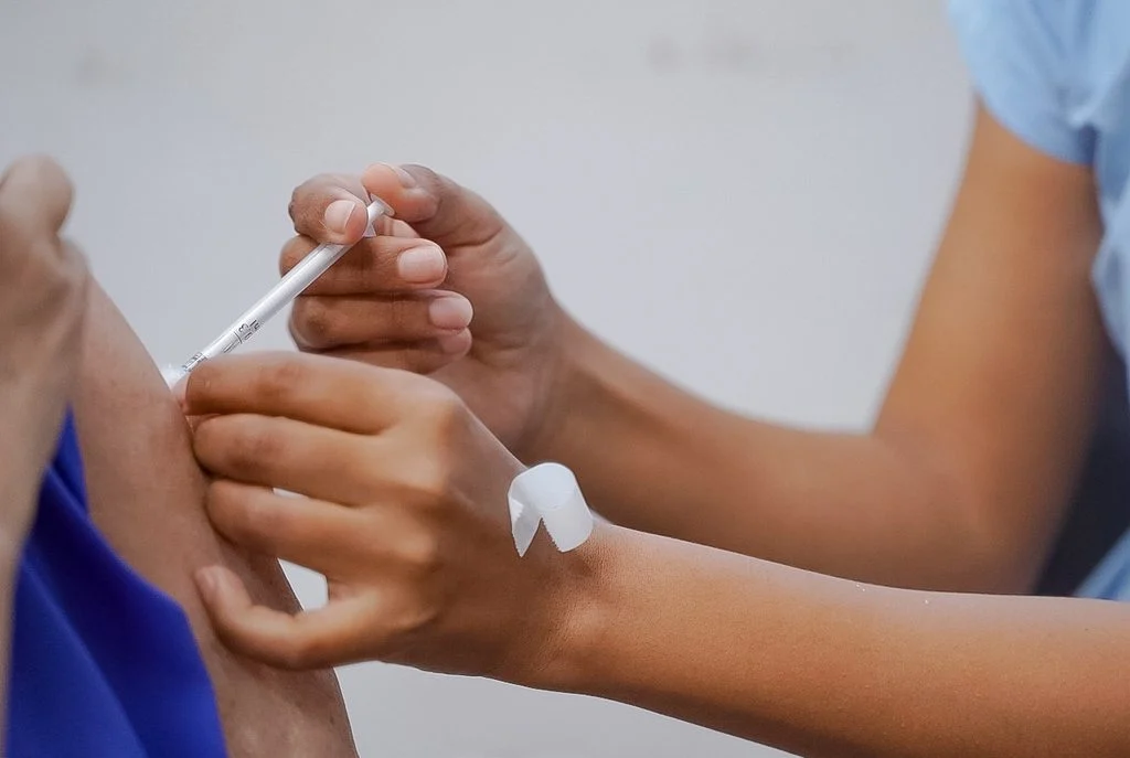 Profissional de saúde aplica vacina em braço de paciente
